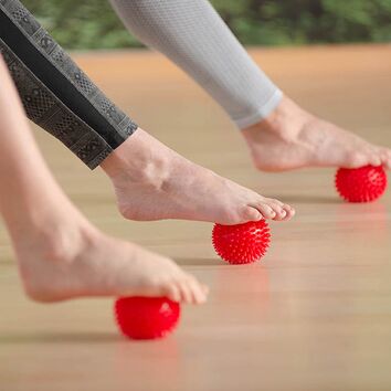 Fussmassager mit Hilfe eines roten Igelballs