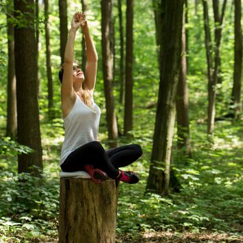 Frau sitz im Yogasitz auf einem Baumstumpf